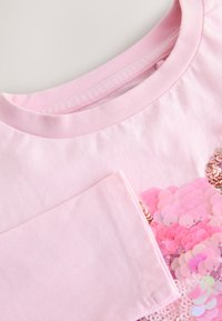 T-shirt en coton rose avec col rond. Présente un motif en sequins brillants dans différentes nuances de rose sur le devant. Comprend un détail de poche.