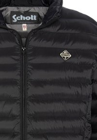 Czarna pikowana kurtka typu puffer z przodem na zamek oraz małym haftowanym logo na lewej piersi. Miękki, wodoodporny materiał.