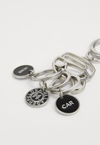 Silver keychain with multiple rings, featuring black circular tags inscribed with "HOME" and "CAR," and a logo disc for Karl Lagerfeld.