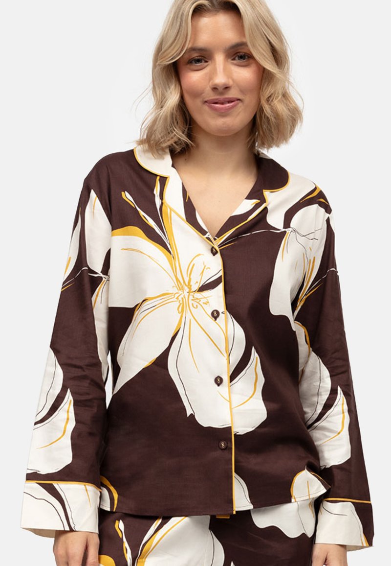 Conjunto de pijama marrón con estampado floral que presenta grandes flores blancas y amarillas, con botones en el frente y mangas largas con ribete amarillo en contraste.