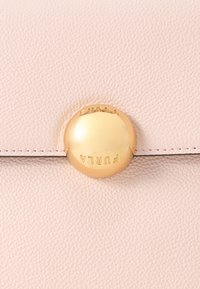 Τσάντα χειρός από ανοιχτό ροζ δέρμα με περίοπτο στρογγυλό κούμπωμα σε χρυσό τόνο με ανάγλυφη την επωνυμία της μάρκας, συνοδευόμενο από διακριτικές ραφές.