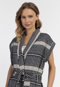 Robe in stile kimono blu navy con motivi geometrici color crema, maniche corte, vita con cintura e tessuto testurizzato.