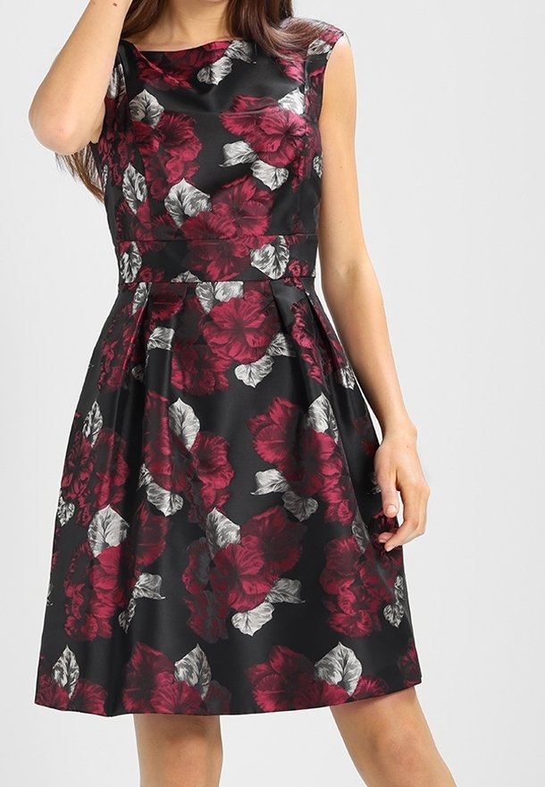 Květinové šaty s černou tkaninou, na které jsou bohaté burgundské květy a šedé listy, přiléhavý korzet a rozšířená sukně sahající až do poloviny lýtek.