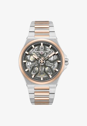 Skeletton automatisch horloge met zilver roestvrij staal en roségouden accenten. Heeft een grijze wijzerplaat, ingewikkeld ontwerp en uurmarkeringen.
