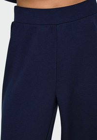 Pantalons de survêtement bleu marine en tissu doux ; dotés d'une taille élastique, de poches frontales et d'une coupe décontractée pour un maximum de confort.