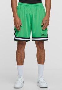 Groene sportshorts van gaas met een zwart-witte gestreepte zoom, met een klein logo op het linkerbeen. Voorzien van een elastische tailleband.