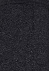 Dark blue fabric with a textured appearance, featuring a subtle pattern and visible stitching details. The material appears sturdy and structured.