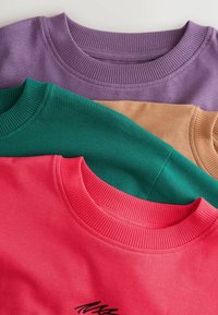 Trys apvalios iškirptės megztiniai, sušalti: purpurinis, žalias, tan ir raudonas. Kiekvienas turi raukinį aplink kaklą ir minkštą, lygų audinį be matomų raštų.