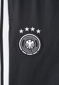 Melns audums ar gludu tekstūru, kuram ir apaļa izšuvuma birka. Birka attēlo ērgļa emblēmu, zvaigznes augšā un "Deutscher Fussball-Bund."