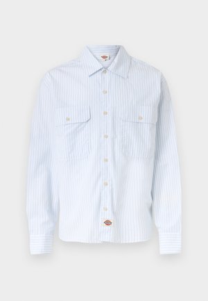 Wit overhemd met dunne blauwe verticale strepen, twee voorste borstzakken met knopen, en een klein logovignet aan de onderzoom.