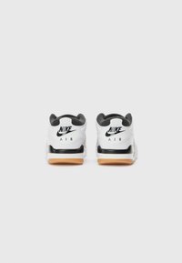 Valkoiset Nike Air -lenkkarit, joissa on mustia yksityiskohtia ja logo, kumipohja, pehmustettu nilkkapanta ja teksturoidut yksityiskohdat kantapäässä ja kielekkeessä.