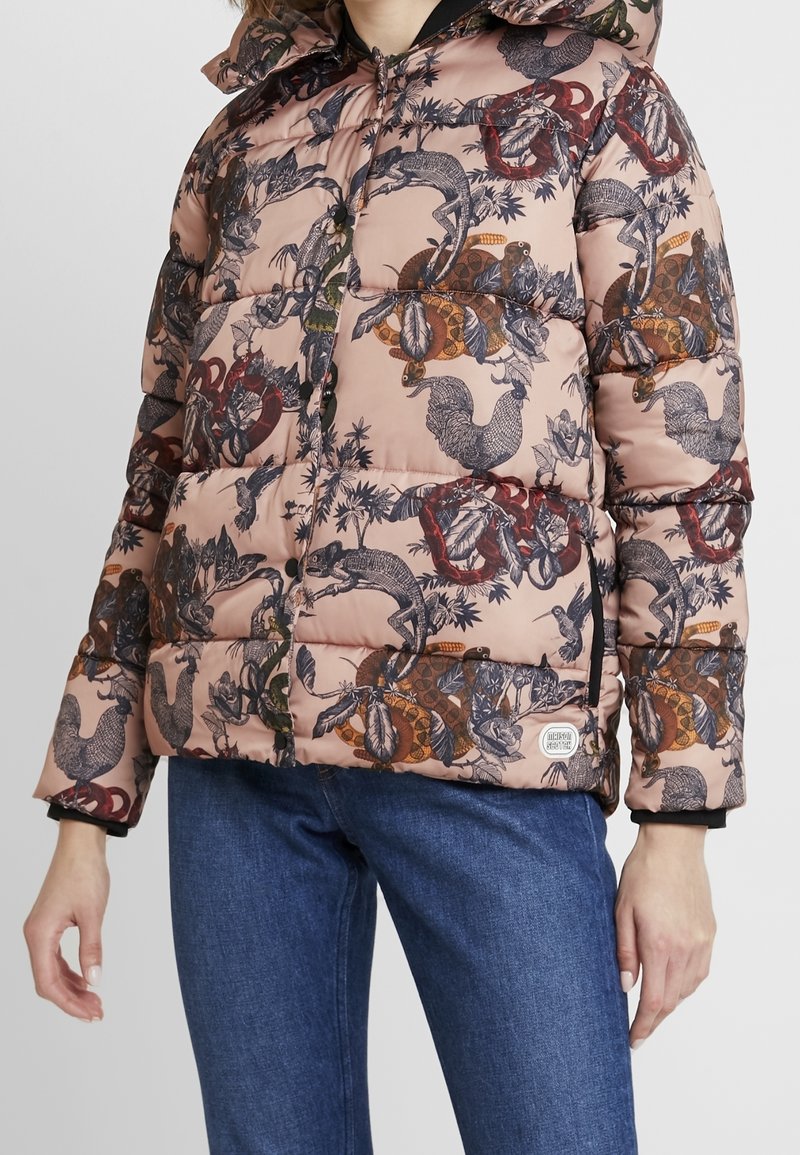 Chaqueta acolchada en rosa suave con intrincadas ilustraciones oscuras de animales y plantas. Presenta una capucha, cierre de cremallera y detalles en las mangas.