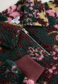 Mikina na zips z flísu v zelenej, bordovej, ružovej a žltej farbe. Má textúrovaný vzor, rebrované manžety a detail so strieborným zipsom.