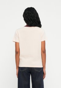 Κοντομάνικο, ανο�ιχτό ροζ μπλουζάκι με μπορντό γιακά. Μαλακό ύφασμα, άνετη εφαρμογή, καθαρές άκρες και ορατές ραφές στο πίσω μέρος.