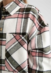 Ternet flannelskjorte i hvid, lyserød og grøn. Har en knaplukket krave, brystlomme og blød tekstur med et markant ternet mønster.