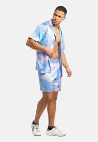 Short-sleeve, collared shirt and shorts set in light blue, featuring a glossy finish with abstract patterns and relaxed fit design.