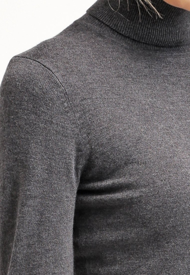 Zbliżenie na osobę noszącą dopasowany, ciemnoszary, prążkowany sweter z golfem i długimi rękawami.