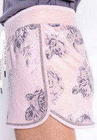 Ljusrosa shorts med blommönster i grått. Mjukt tyg, elastisk midja, rundad nederkant, synlig sömnad längs kanterna.