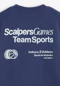 Camiseta de algodón azul marino con texto blanco, que incluye "Scalpers Games Team Sports" y un gráfico de baloncesto. Corte relajado, cuello redondo.