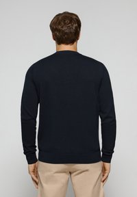 Laivastonsininen neulepusero pyöreällä pääntiellä ja pitkillä hihoilla, tehty neuloksesta. Varustettu resorireunuksilla hihoissa ja helmassa, yksinkertaisella ja siistillä designilla.