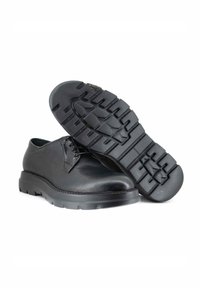 Scarpe in pelle nera con punta arrotondata, design con lacci e suola in gomma spessa con un motivo a battistrada testurizzato.