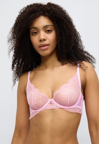 Φούξια ροζ δαντελένιο σουτιέν με σχέδιο από λουλουδάτο δίχτυ, κυματιστά τελειώματα και μικρό φιόγκο στο κέντρο. Διακοσμημένο με βολάν.