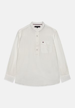 Biała koszula z długim rękawem, stójką, guzikami z przodu, lewą kieszenią na piersi oraz małą naszywką z logo. Bawełniana tkanina o gładkiej fakturze.