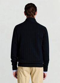 Pull en maille côtelée bleu marine avec col montant et manches longues, présentant une taille ajustée et un tissu texturé. Poignets superposés visibles.