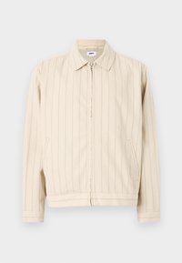 Beige zip-up jacket with vertical light blue stripes. Features a collar, two side pockets, and a straight hem. Made of cotton fabric.