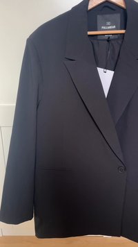 Zwarte blazer met een reverskraag, enkele knoopsluiting en zijzakken. Gemaakt van gladde stof, met een strak, minimalistisch ontwerp.