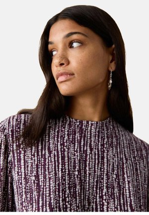 Blusa morada con estampado y superficie texturizada, con cuello alto y mangas largas. Incluye pequeños pendientes colgantes.