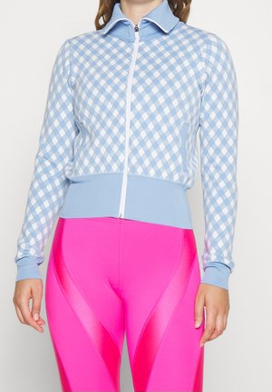 Cardigan zippé bleu clair avec un motif en losange blanc, doté de poignets et d'ourlet côtelés. Assorti à des leggings roses vifs.