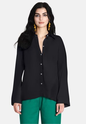Zwarte knoopshirt met kraag, lange mouwen en een ontspannen pasvorm. Gecombineerd met groene broek, met een gladde textuur en subtiele glans.