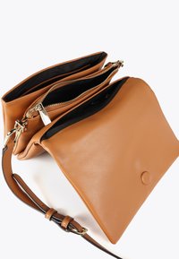 Borsa a tracolla in pelle marrone con doppie tasche con zip, che mostrano una foderatura nera all'interno. Un tracollo removibile è attaccato sul lato.