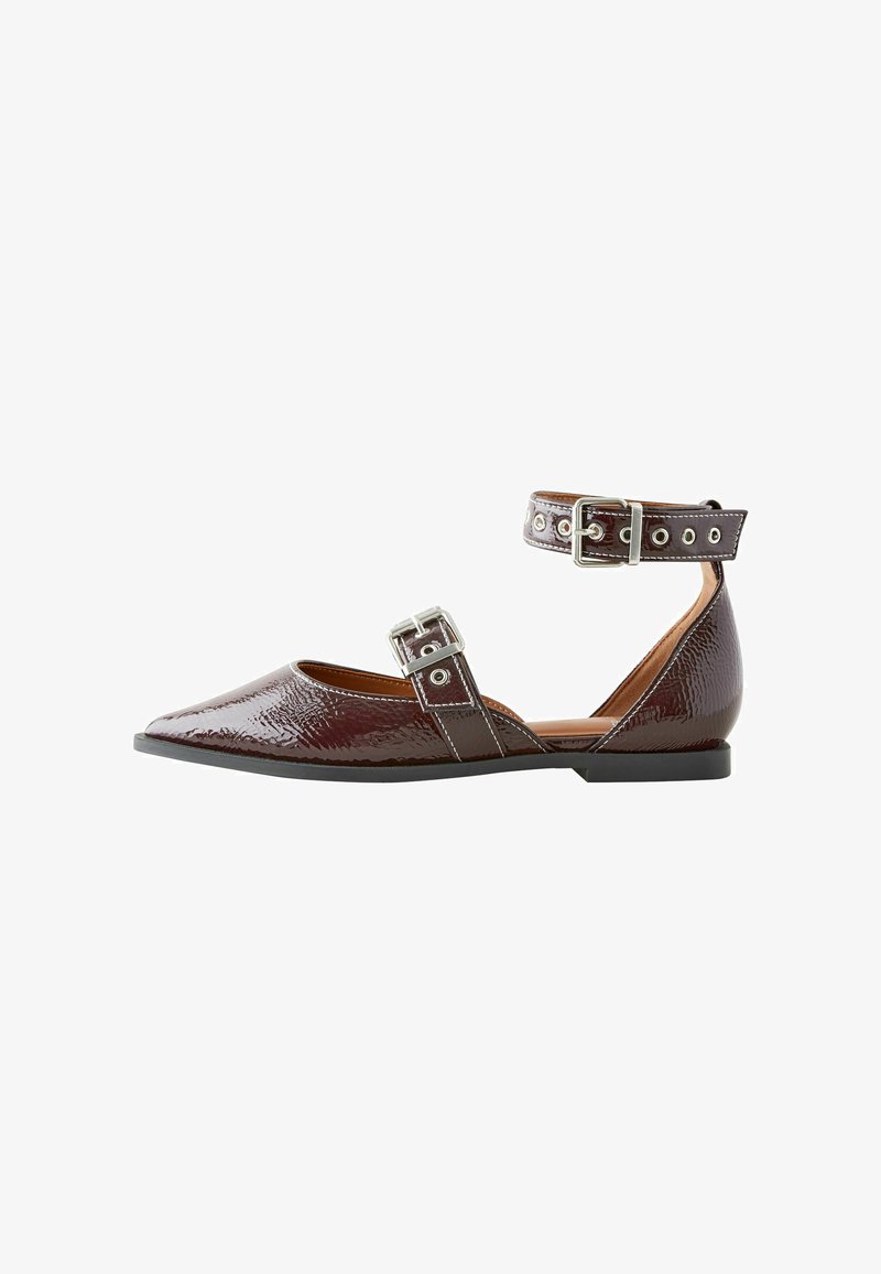 Chaussure plate en cuir verni bordeaux avec un bout pointu, sangle de cheville ajustable avec boucle en métal et accents de rivets, petit talon noir.