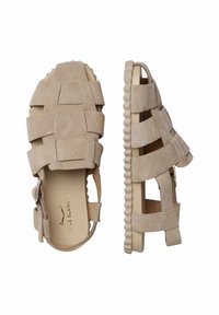 Sandalias de ante beige con múltiples correas, diseño de talón descubierto y suela de goma texturizada gruesa. Cuenta con un cierre lateral para un ajuste seguro.