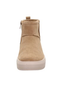 Botín de ante beige hasta el tobillo con cremallera lateral, puntera redonda y suela de plataforma blanca. Presenta un diseño sencillo con un acento cosido cerca del tobillo.