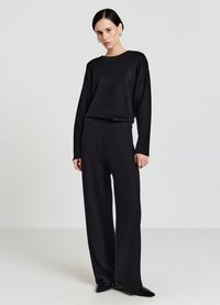 Schwarzer Strickpullover mit rundem Ausschnitt und langen Ärmeln, kombiniert mit passenden, hoch taillierten Hosen mit weitem Bein. Glatte Textur, minimalistisches Design.