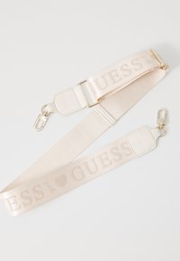 Rem har lavet af lyserød stof med en glat tekstur. Har et præget "GUESS" logo og hardwareklip i guld tone til fastgørelse.