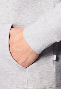 Szary sweatshirt o miękkiej fakturze, z kieszenią kangurką i ściągaczami na rękawach. Materiał jest lekko marmurkowy, co dodaje wizualnego interesu.