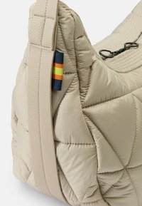 Borsa a spalla beige trapuntata con un design testurizzato e imbottito. Presenta un'etichetta distintiva multicolore e una tracolla resistente e liscia.