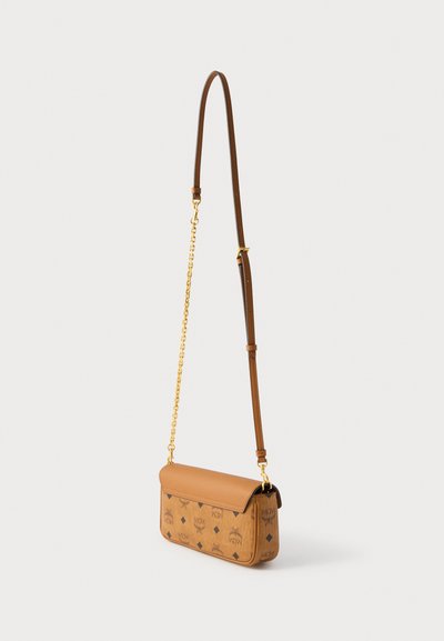 Μικρή ταν τσάντα χιαστί με σκούρα καφέ λογότυπα MCM, χρυσή αλυσίδα και ρυθμιζόμενο δερμάτινο λουρί σε λευκό φόντο.