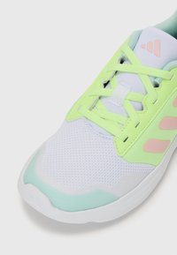 Scarpe atletiche leggere con tomaia in mesh bianco, arricchita da accenti verde menta e giallo neon, completata da dettagli e lacci rosa chiaro.