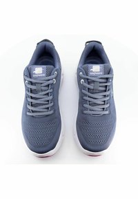 Grå sportskor med överdel i mesh, mönstrad design, platta snören och vita sulor. Logotyp synlig på tungan. Minimalistisk stil.