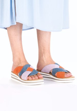Colorful slide sandals with a cross-strap design. Made of purple, blue, and orange leather on a white platform sole with stripes.