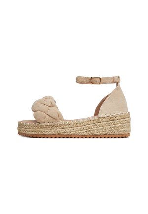 Beżowy sandał na koturnie z zamszu, z plecionym paskiem na palce, zapinką przy kostce oraz platformą z juty. Podeszwa o fakturze oraz kontrastujące detale przeszyć.