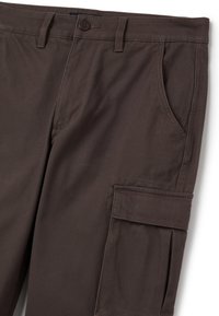 Braune Cargo-Hosen aus strapazierfähigem Stoff mit flachem Vorderteil, seitlichen Taschen und einer markanten Cargo-Tasche am Bein.