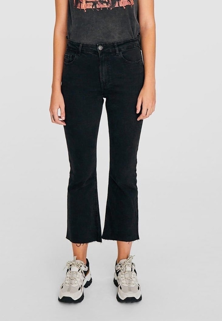 Jeans neri a campana con orlo grezzo, realizzati in denim, con vita alta e dettagli di cucitura minimi. Abbinati a sneaker di colore neutro.