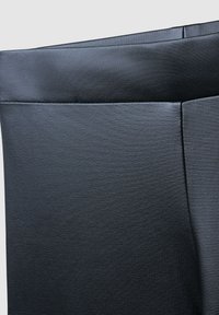 Czarna spódnica imitująca skórę o gładkiej fakturze, z starannie przeszytymi szwami i czystą, uporządkowaną sylwetką.