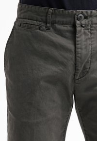 Pantaloni slim-fit grigi scuri realizzati in tessuto leggero. Presentano una chiusura con bottone, tasche laterali e posteriori, e una texture liscia.